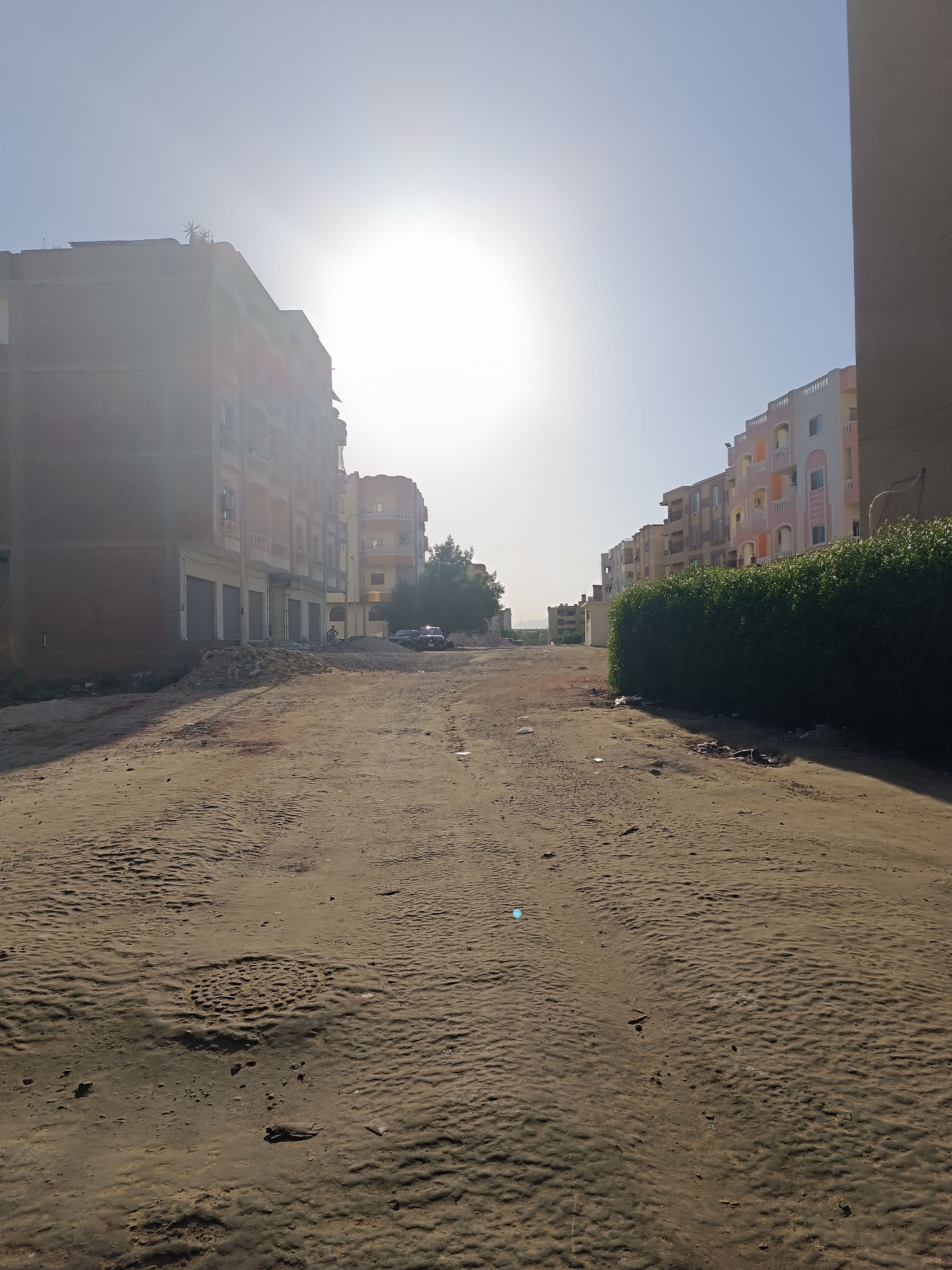 A quiet unpaved street in Luxor at midday